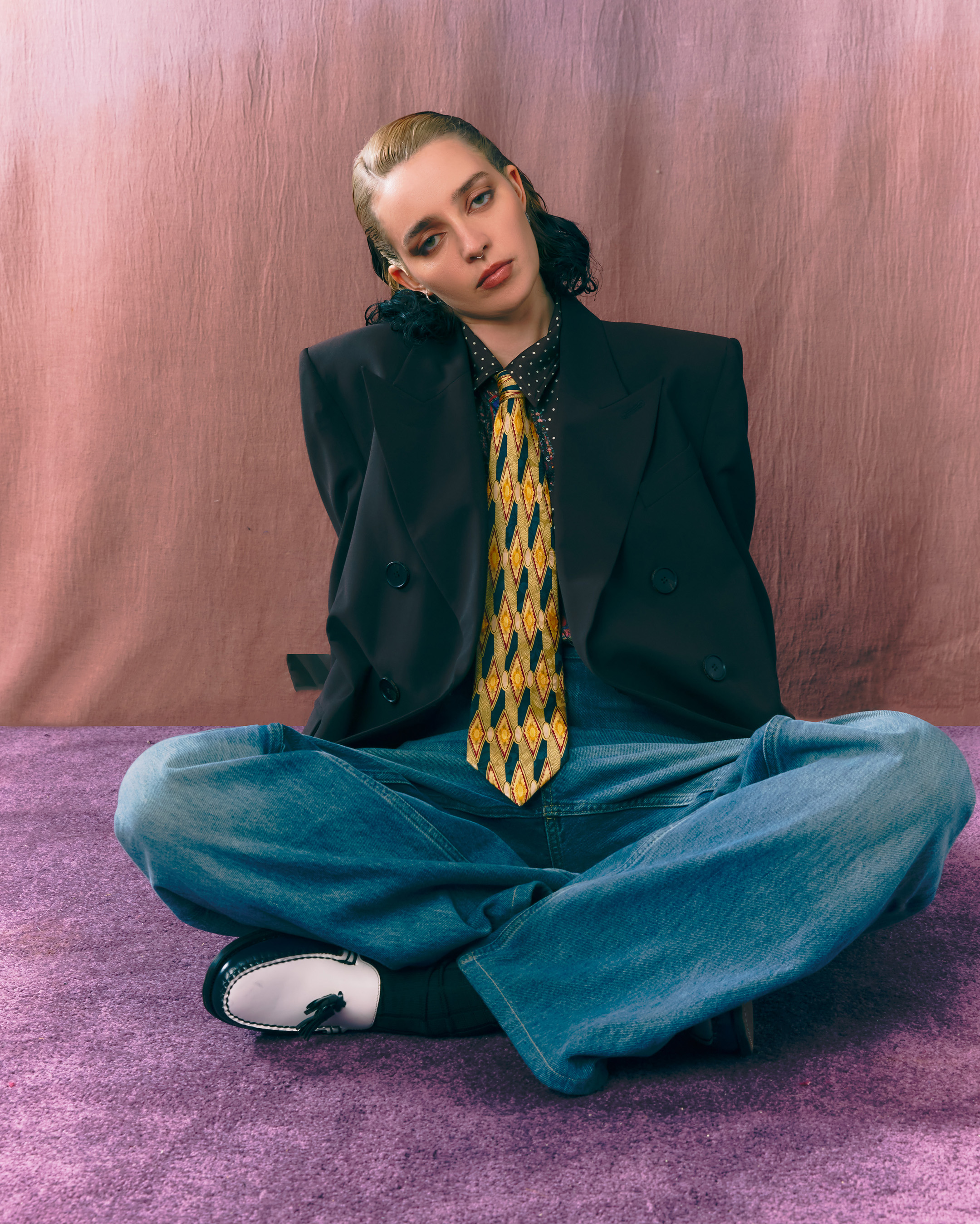 Gia Ford in a black blazer, jeans and a patterned yellow tie, photo by Melanie Lehmann